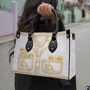 Angled view displaying the metallic gold dermatology uniform artwork printed across the handbag.