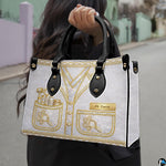 Angled view displaying the metallic gold dermatology uniform artwork printed across the handbag.