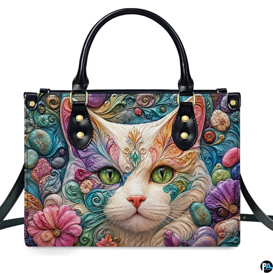 Front studio shot of white cat emerald eyes and sculpted filigree, flowers, and pebbles.