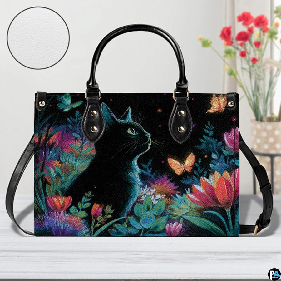 Front view of whimsical black cat art on white wooden surface beside red floral vase.