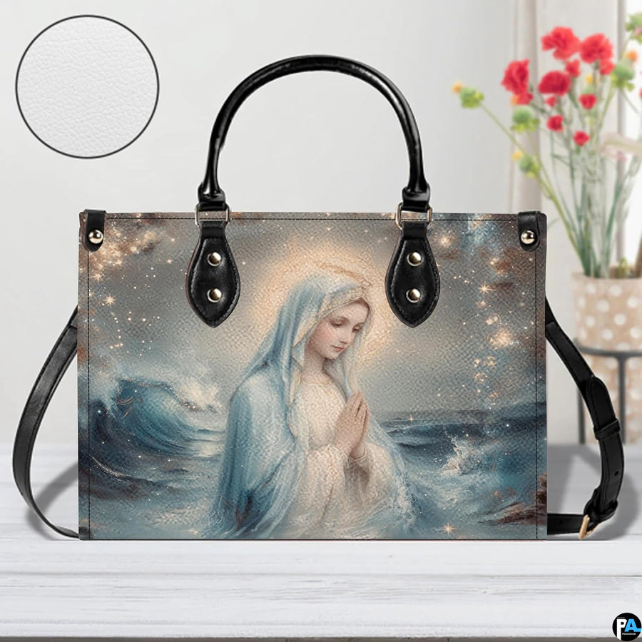 Tabletop lifestyle display of Our Lady Star of the Sea handbag beside flower vase.