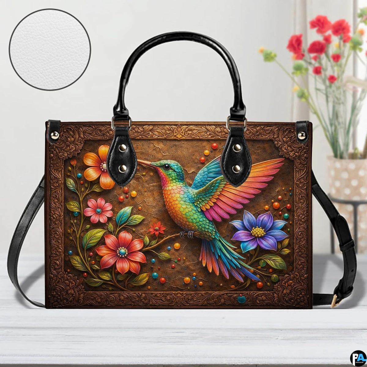 Studio front shot of handbag showcasing rainbow-winged hummingbird perched within filigree border.