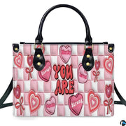Front view of pink affirmation handbag showing conversation candy hearts on checkerboard ground.