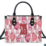 Front view of pink affirmation handbag showing conversation candy hearts on checkerboard ground.