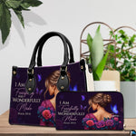 Woman portrait handbag and matching wallet displayed on a wooden surface beside decorative greenery.