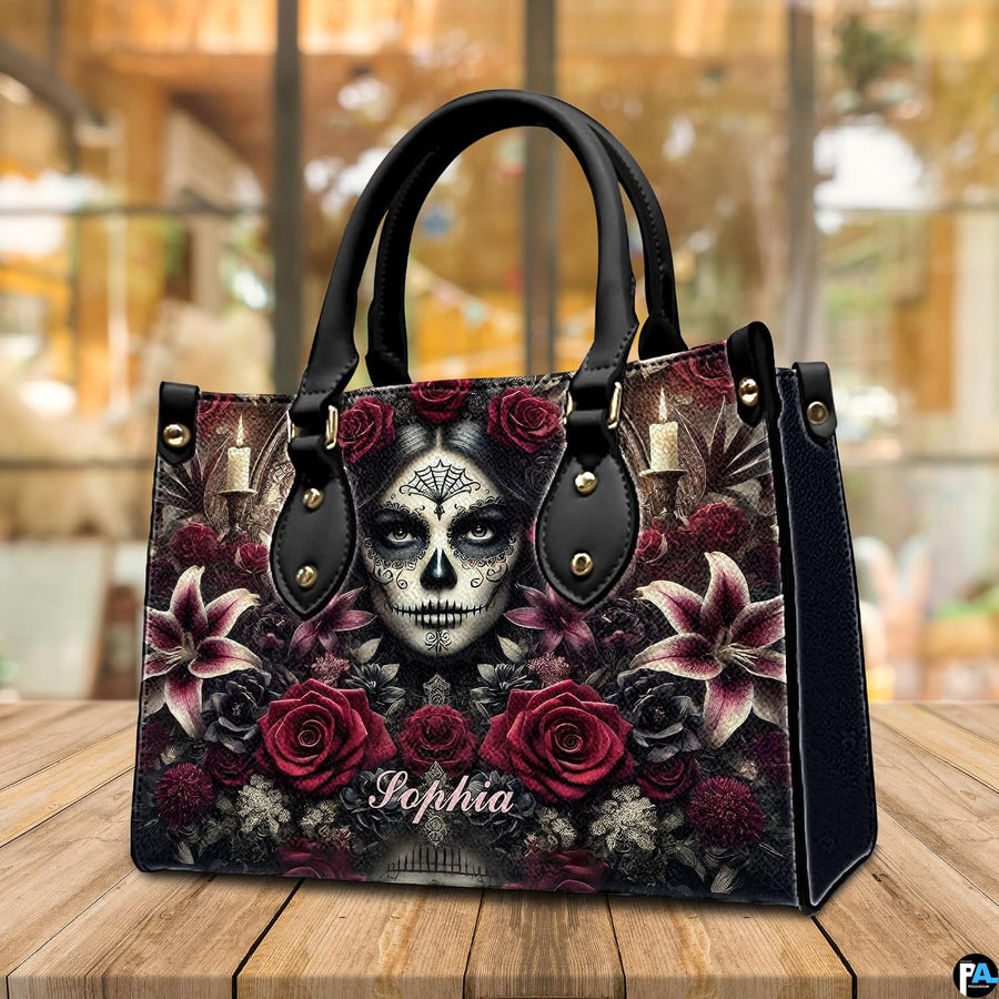 Dia de los Muertos handbag displayed on wooden tabletop in front of sunlit windows.