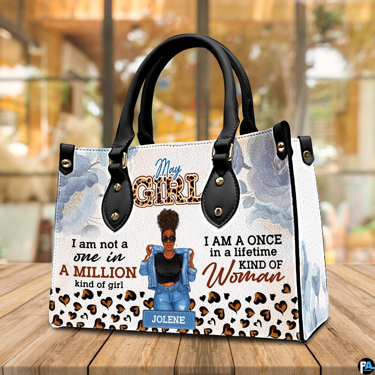 Perspective view of afro puff art accessory resting on wooden table before bright window reflection.