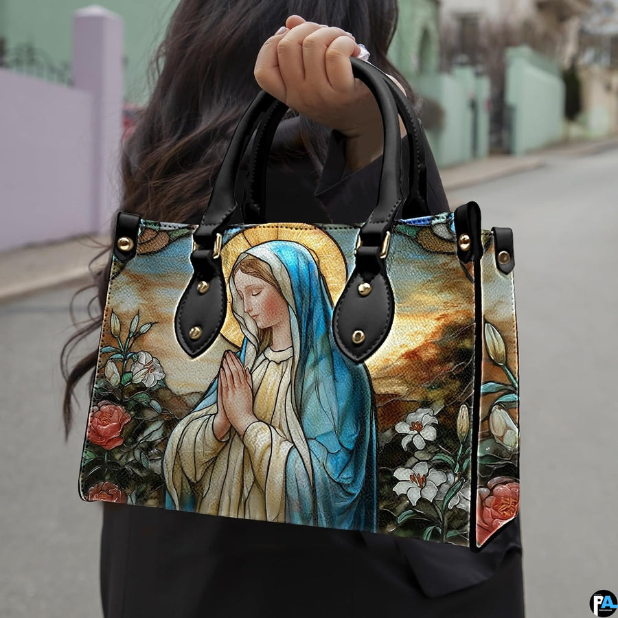 Model wearing stained glass Virgin Mary handbag over shoulder with strap.