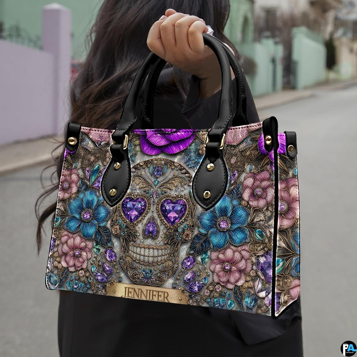 Jeweled skull handbag carried outdoors by top handle along residential street.