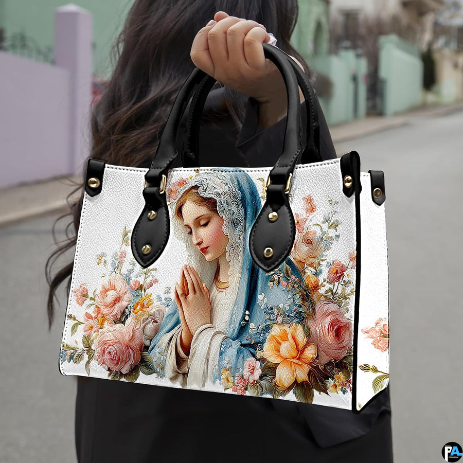 Lifestyle presentation of praying Madonna handbag with blush rose bouquet.