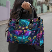 Front view of celestial moth handbag with rainbow wings and glowing crescent moon over meadow