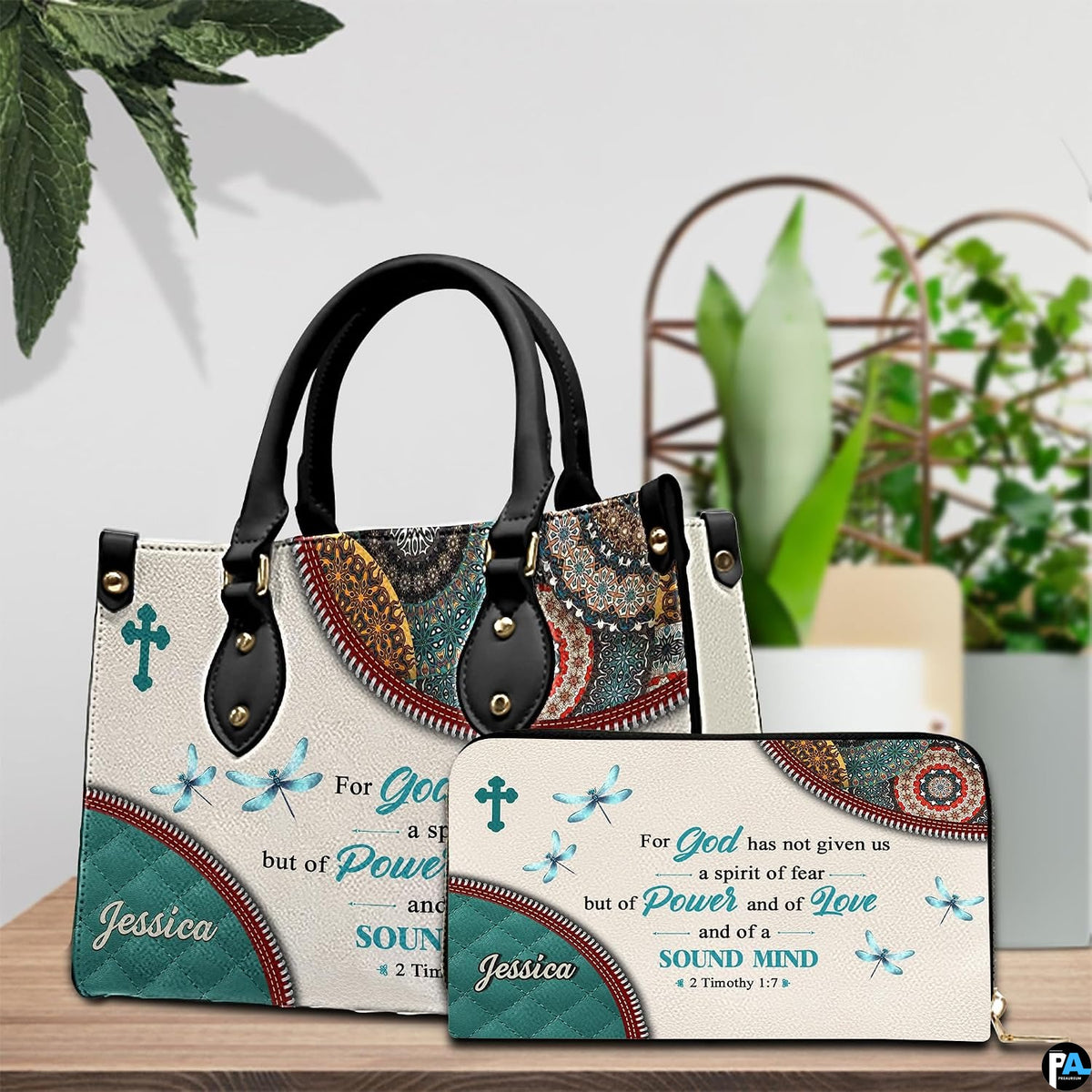 Matching scripture verse handbag and wallet displayed on wooden table with plants.