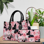 Tabletop display of black butterfly and pink daisy handbag set