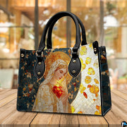 Stained glass mosaic Virgin Mary handbag displayed in three-quarter view on wooden table.