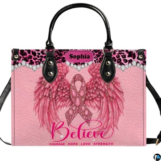 Pink angel wings art accessory displaying jeweled ribbon, feathered wings, and leopard trim on pink paneling.