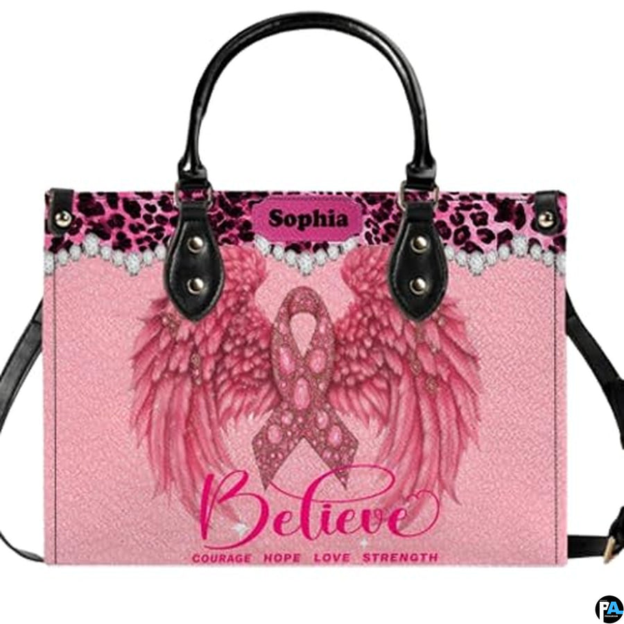 Pink angel wings art accessory displaying jeweled ribbon, feathered wings, and leopard trim on pink paneling.