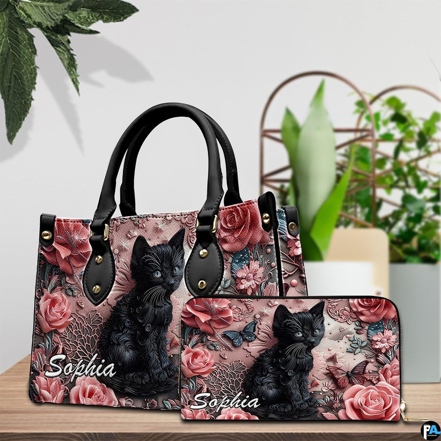 Sculpted black cat and floral artwork displayed on a wooden surface beside house plants.