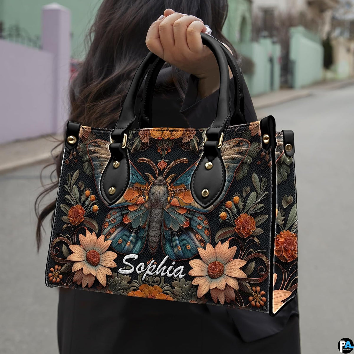 Model holding gothic peacock moth botanical handbag outdoors