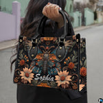 Model holding gothic peacock moth botanical handbag outdoors