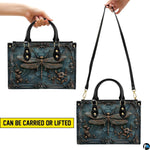 Top view of bronze dragonfly handbag showing zippered top closure and dual structured handles