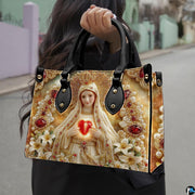 Model wearing Our Lady of Fatima handbag over shoulder with attached strap.