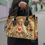 Model wearing Our Lady of Fatima handbag over shoulder with attached strap.