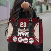 Front view of baseball handbag featuring bold curved red laces and maroon athletic panels.