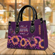 Tabletop perspective of purple sunflower handbag standing upright on wooden surface