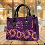 Tabletop perspective of purple sunflower handbag standing upright on wooden surface