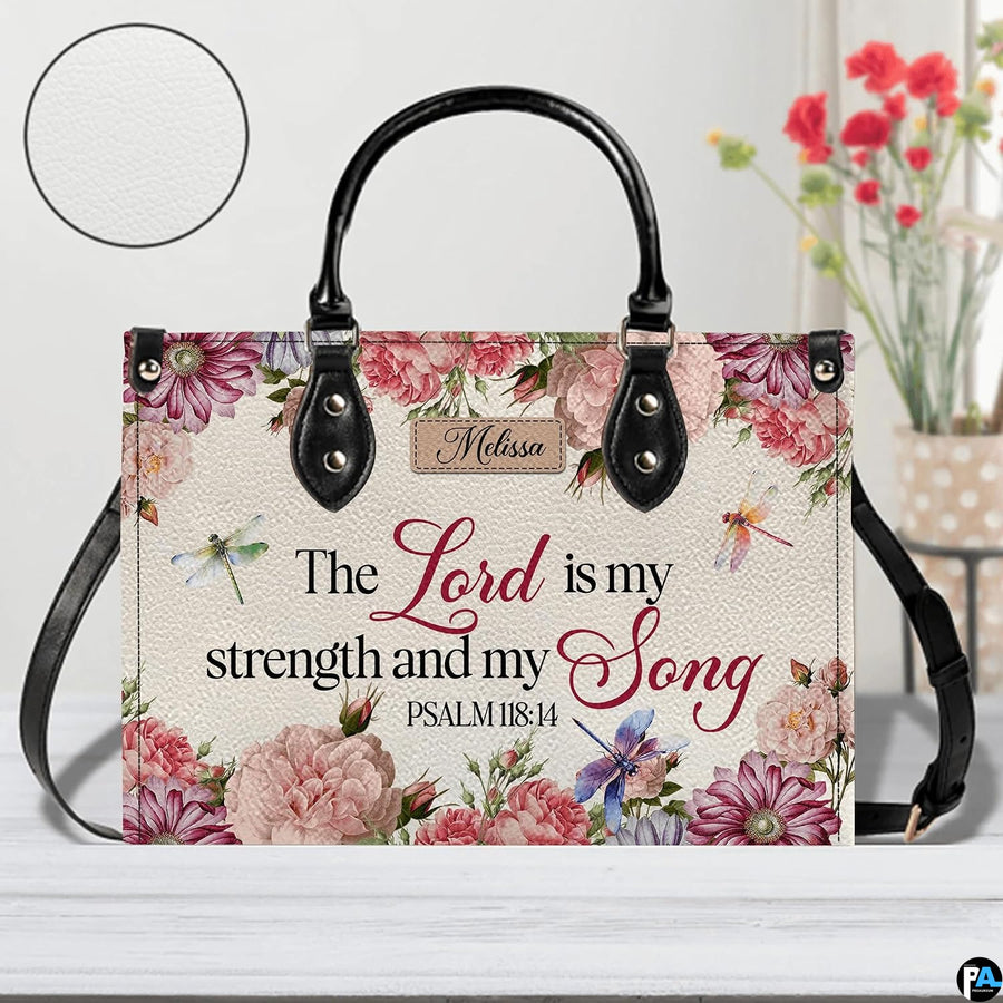 Scripture floral dragonfly handbag displayed on white table beside floral bouquet.