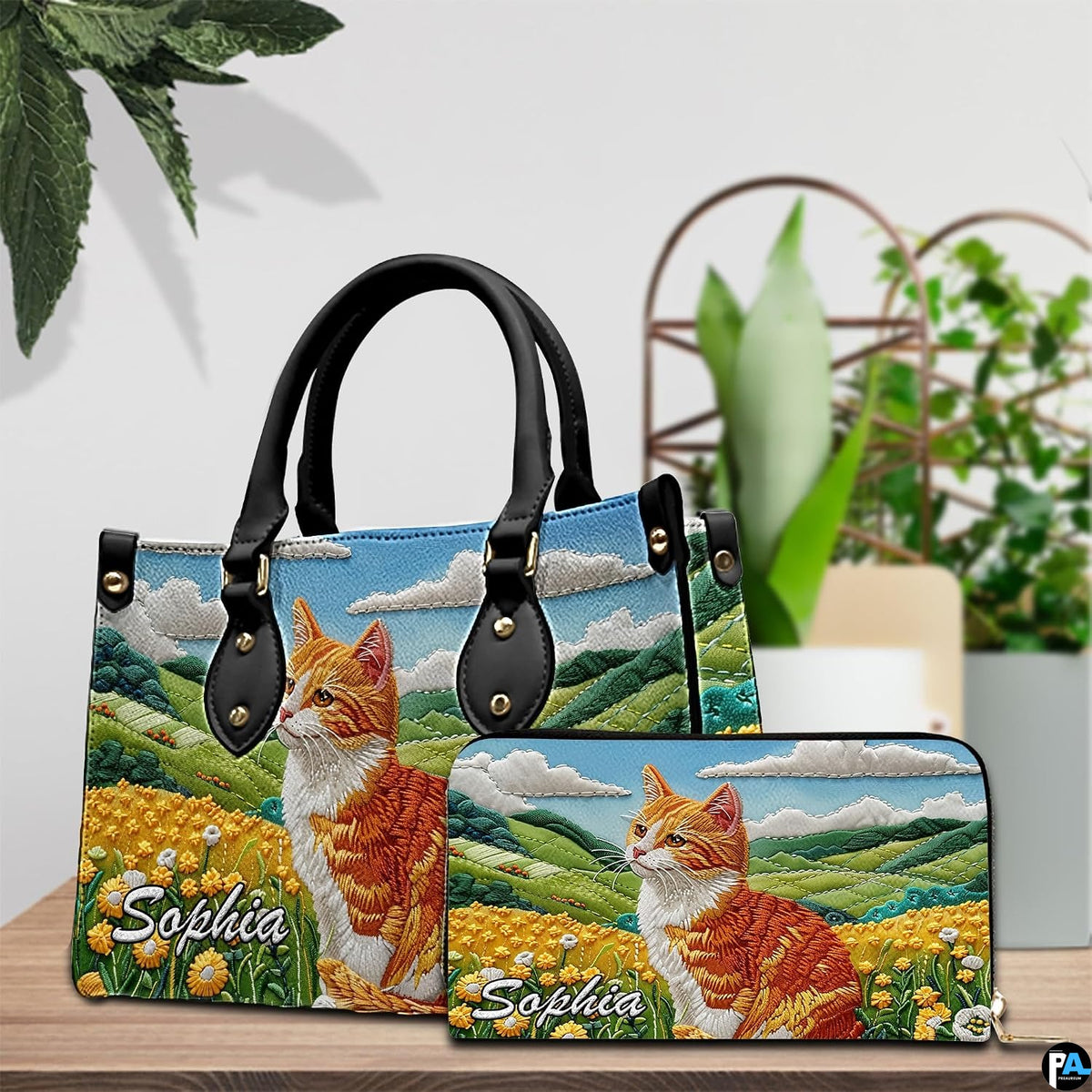 Ginger cat and wildflower meadow artwork displayed on wooden table beside houseplants.