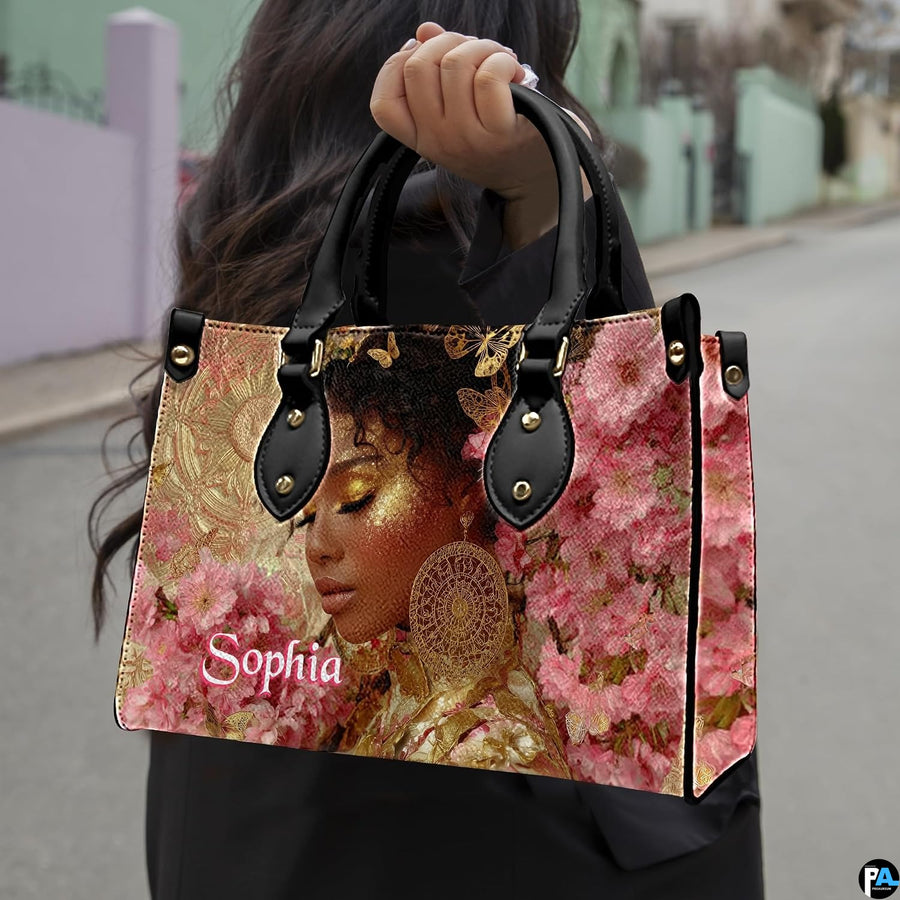 Outdoor view showing model carrying golden glow afro art accessory by top handle in natural light.