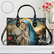 Sunlit outdoor view highlighting colorful stained glass Marian artwork on handbag.