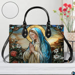 Sunlit outdoor view highlighting colorful stained glass Marian artwork on handbag.