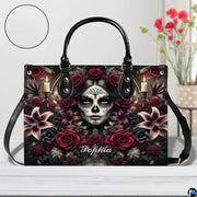 Sugar skull handbag displayed on white table beside floral bouquet.