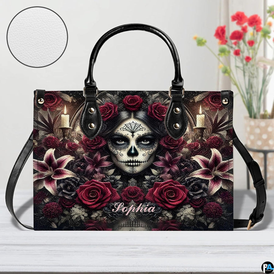 Sugar skull handbag displayed on white table beside floral bouquet.