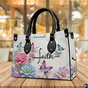 Close-up front view of pastel floral blossoms and calligraphy cross on structured tote handbag
