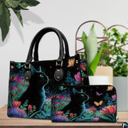 Tabletop presentation showing black cat flowers art on wood beside green houseplants.