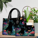Tabletop presentation showing black cat flowers art on wood beside green houseplants.