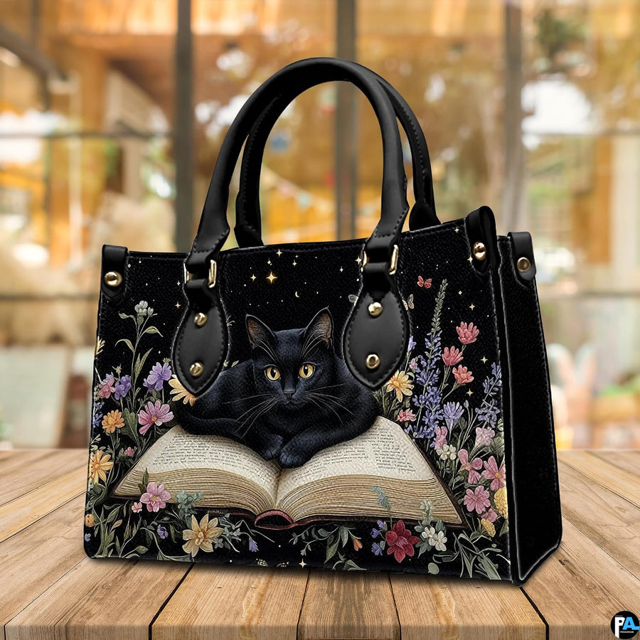 Indoor cafe table arrangement showing bookish black cat artwork before sunlit window.
