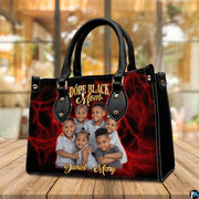 Side profile view of structured crimson handbag showing sleek silhouette and dark carrying handles.