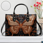 Sculpted bronze butterfly handbag shown on a white tabletop with floral decor.