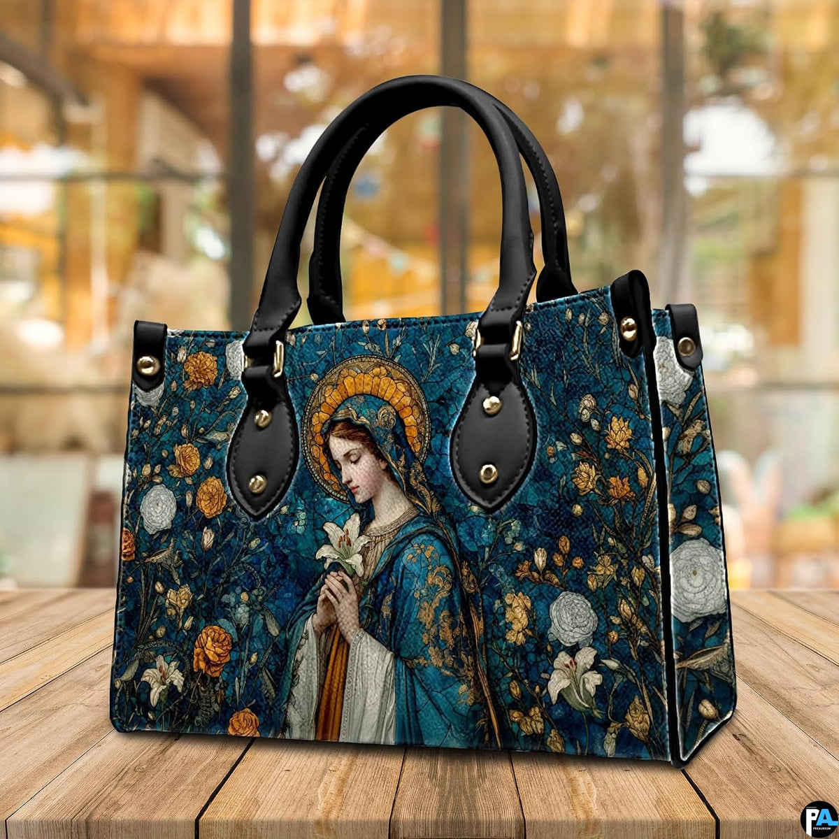 Madonna mosaic sacred art handbag resting on a wooden cafe tabletop with warm background lighting