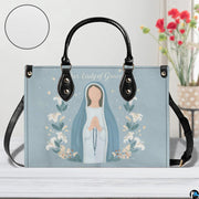 Minimalist Marian praying handbag displayed on white table with floral background