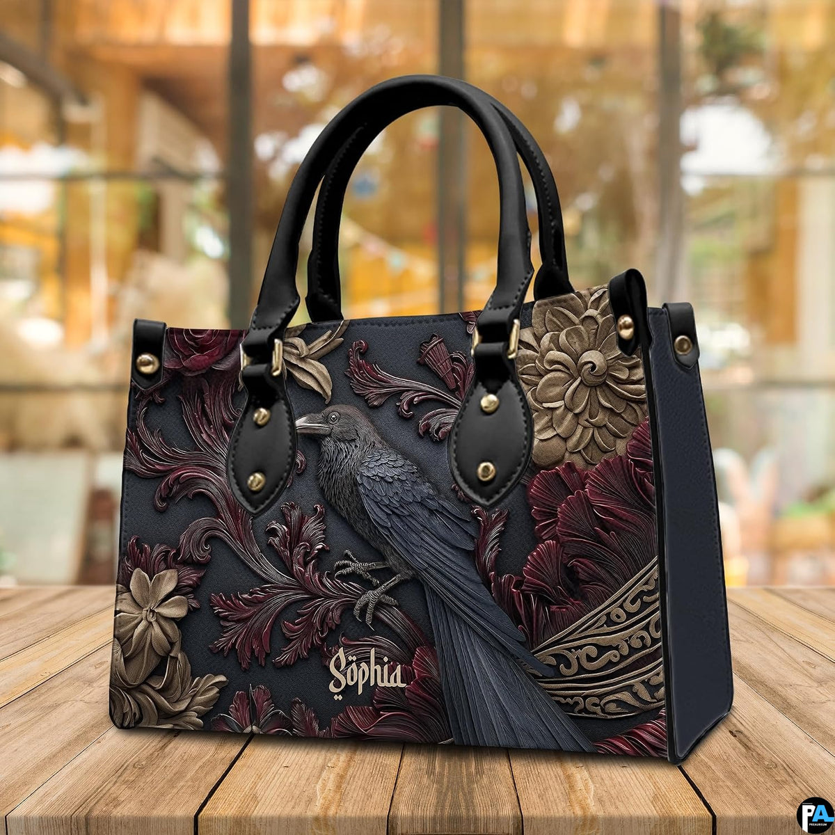 Gothic raven handbag and wallet on wooden table beside houseplant and wire trellis.