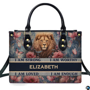 Frontal view of handbag featuring a painted lion portrait amidst vintage pink roses, butterflies, and affirmation banners.