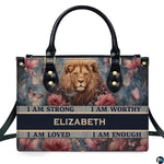 Frontal view of handbag featuring a painted lion portrait amidst vintage pink roses, butterflies, and affirmation banners.