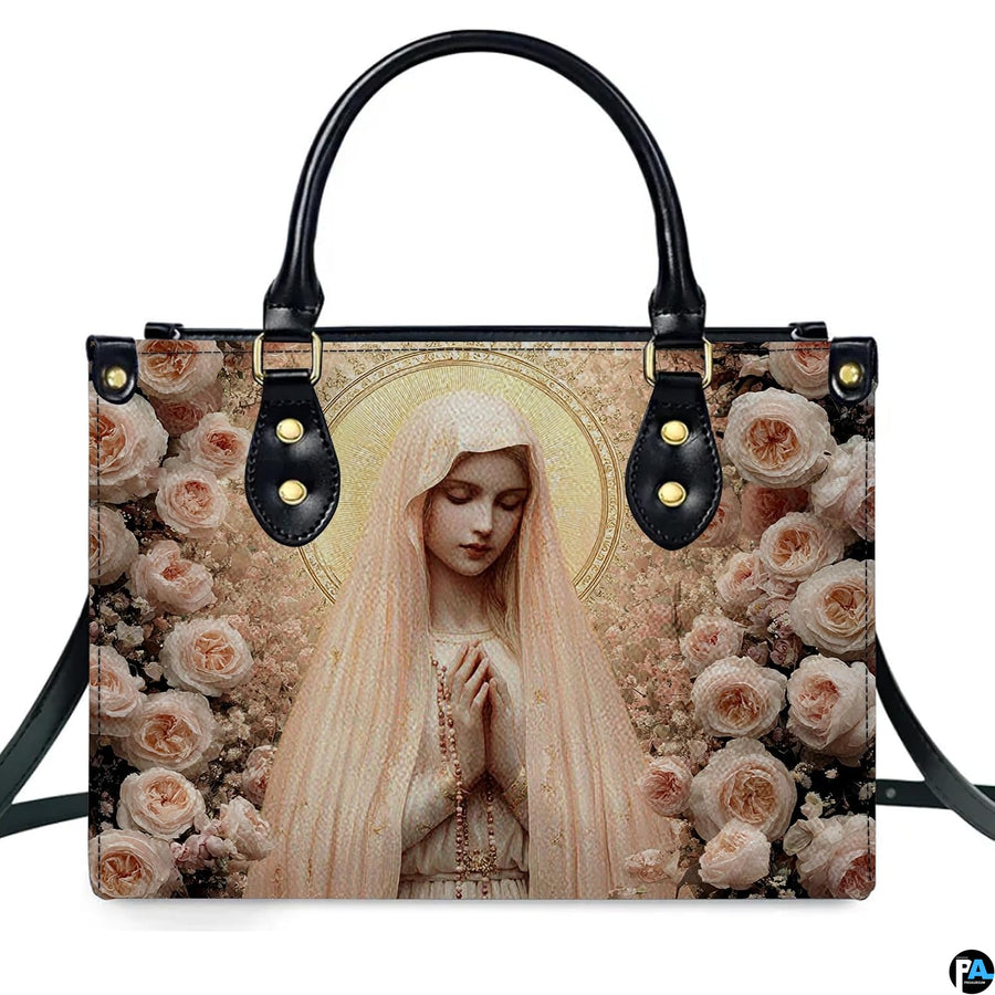 Front view of handbag displaying praying Virgin Mary encircled by lush blush pink and peach cabbage roses.