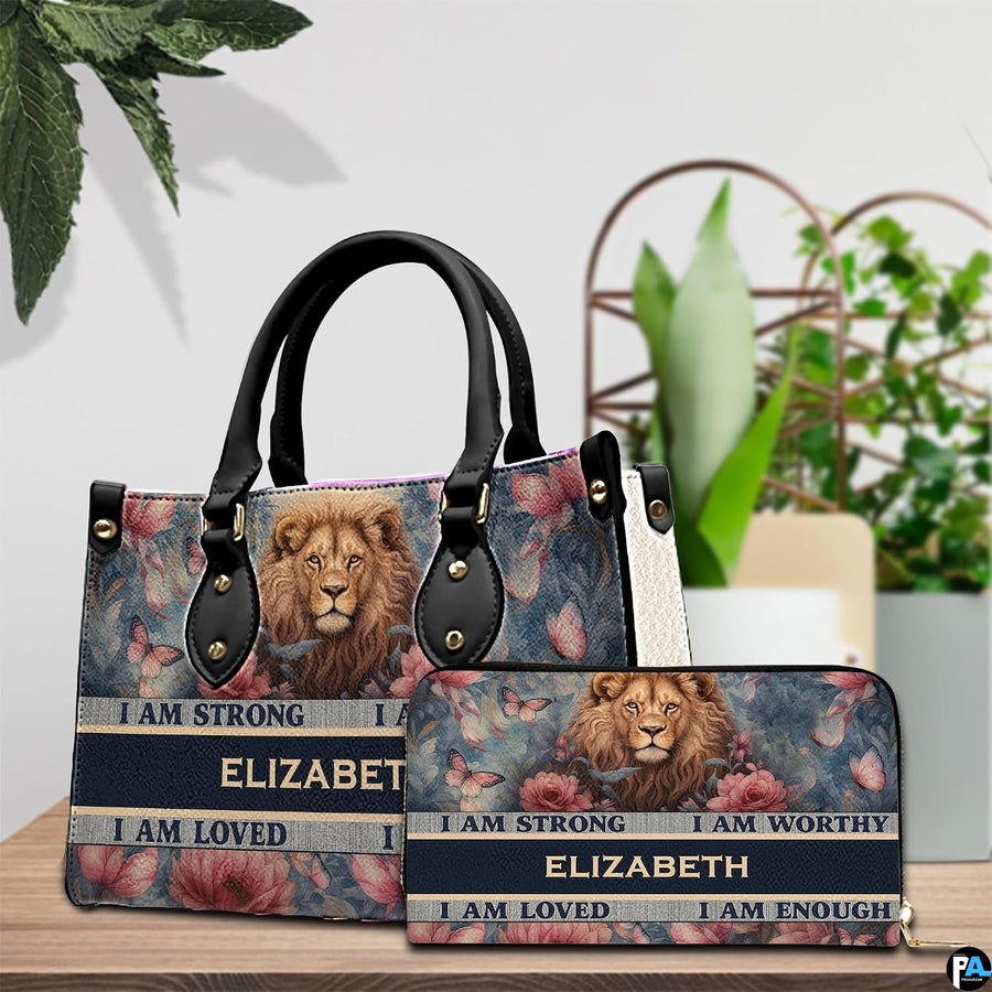 Lion portrait handbag and matching zip wallet shown together on wooden tabletop beside houseplant.