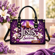 Purple cross devotional handbag displayed on a marble tabletop beside a vase of white lilies and candle.